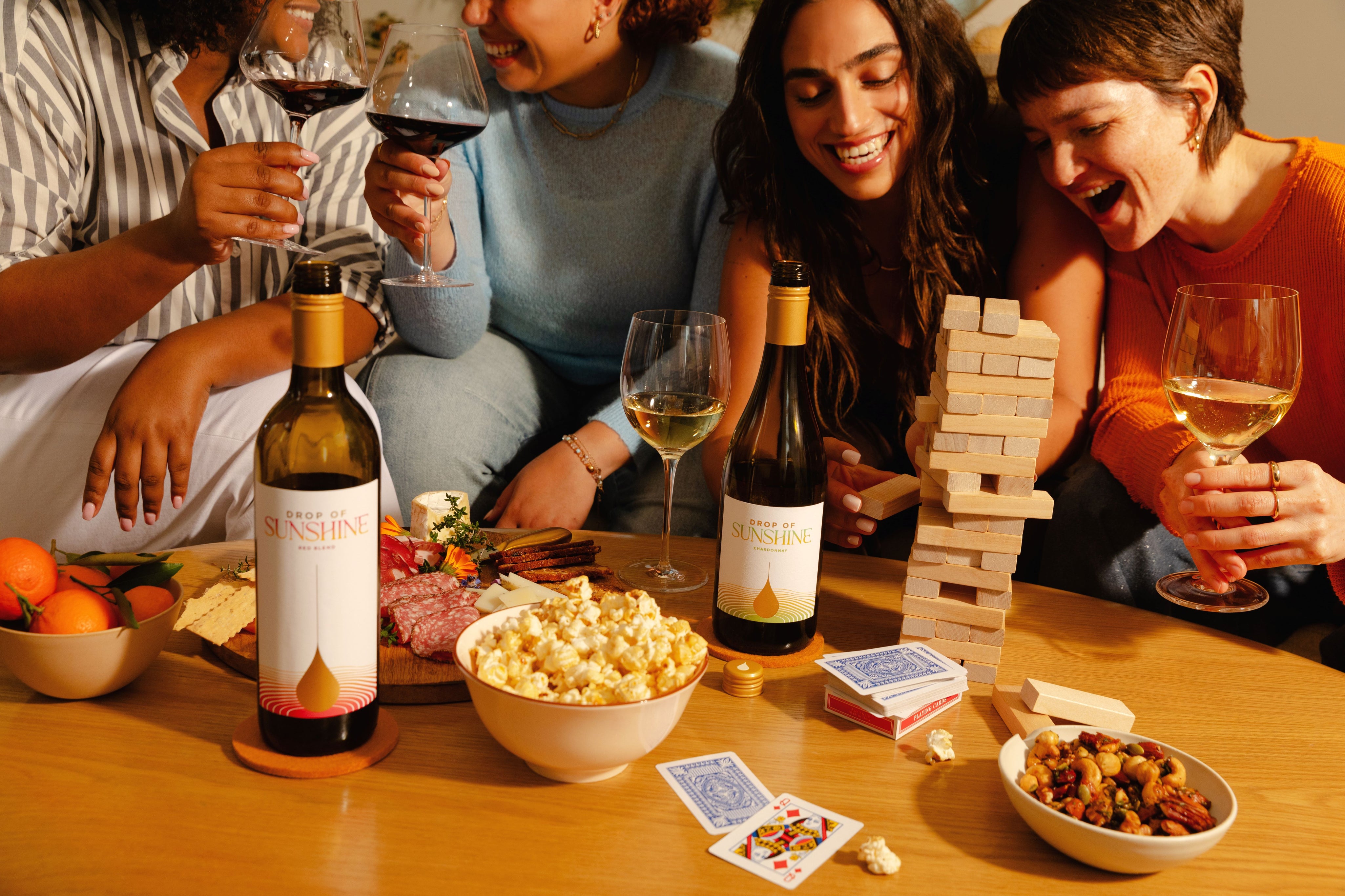 Four women sitting around a table each with a glass of wine playing games together