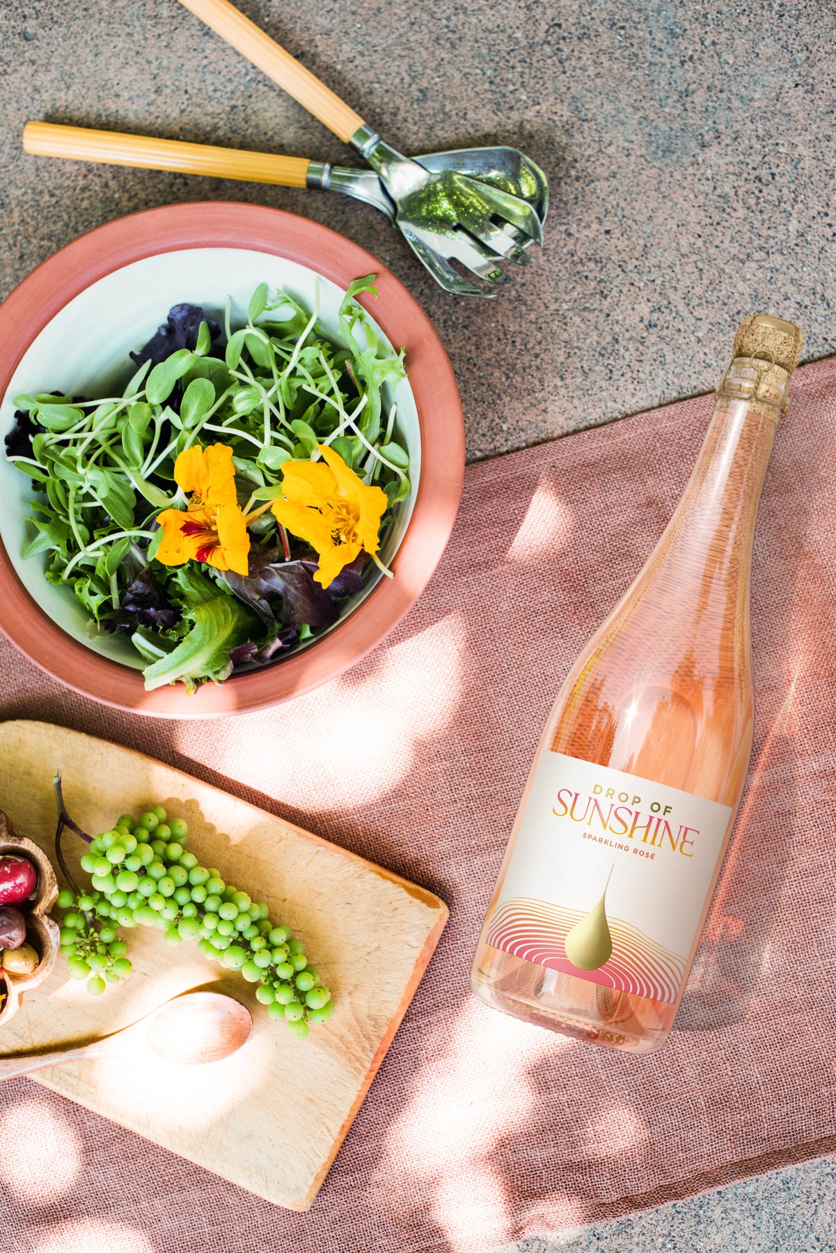 Drop of Sunshine Sparkling Rosé paired with salad edible flowers and fruit laying won a table with linen