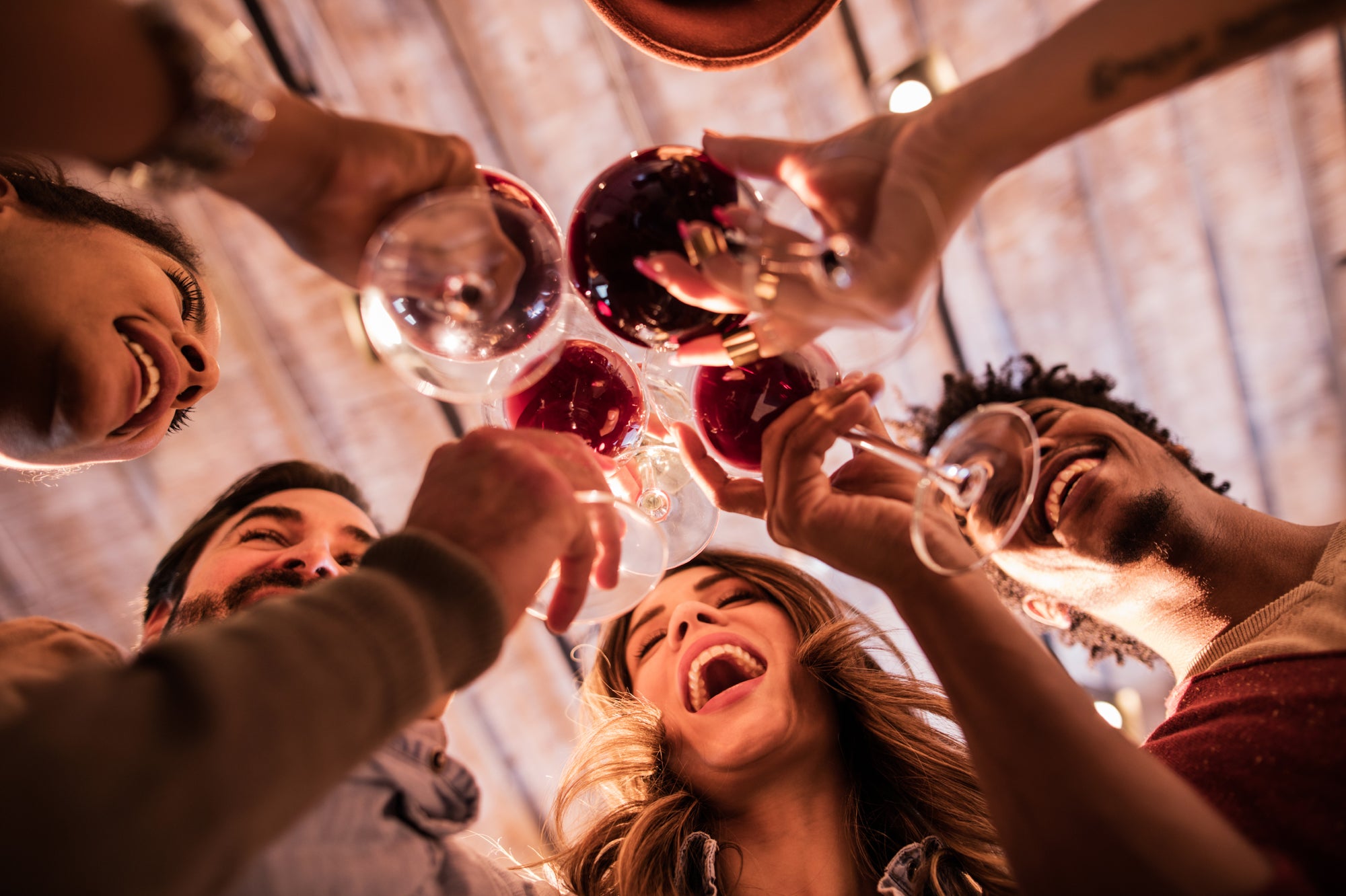 a group of people laughing and cheersing with red wine