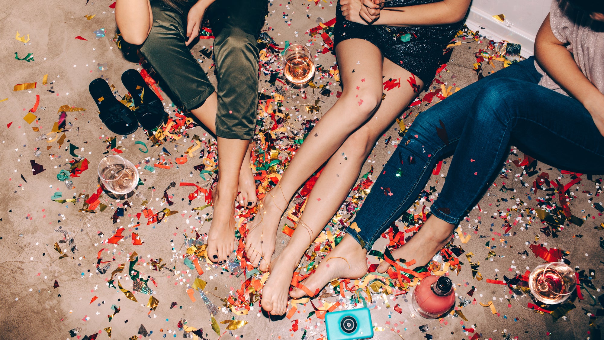 women sitting on the floor surrounded by confetti and wine. 