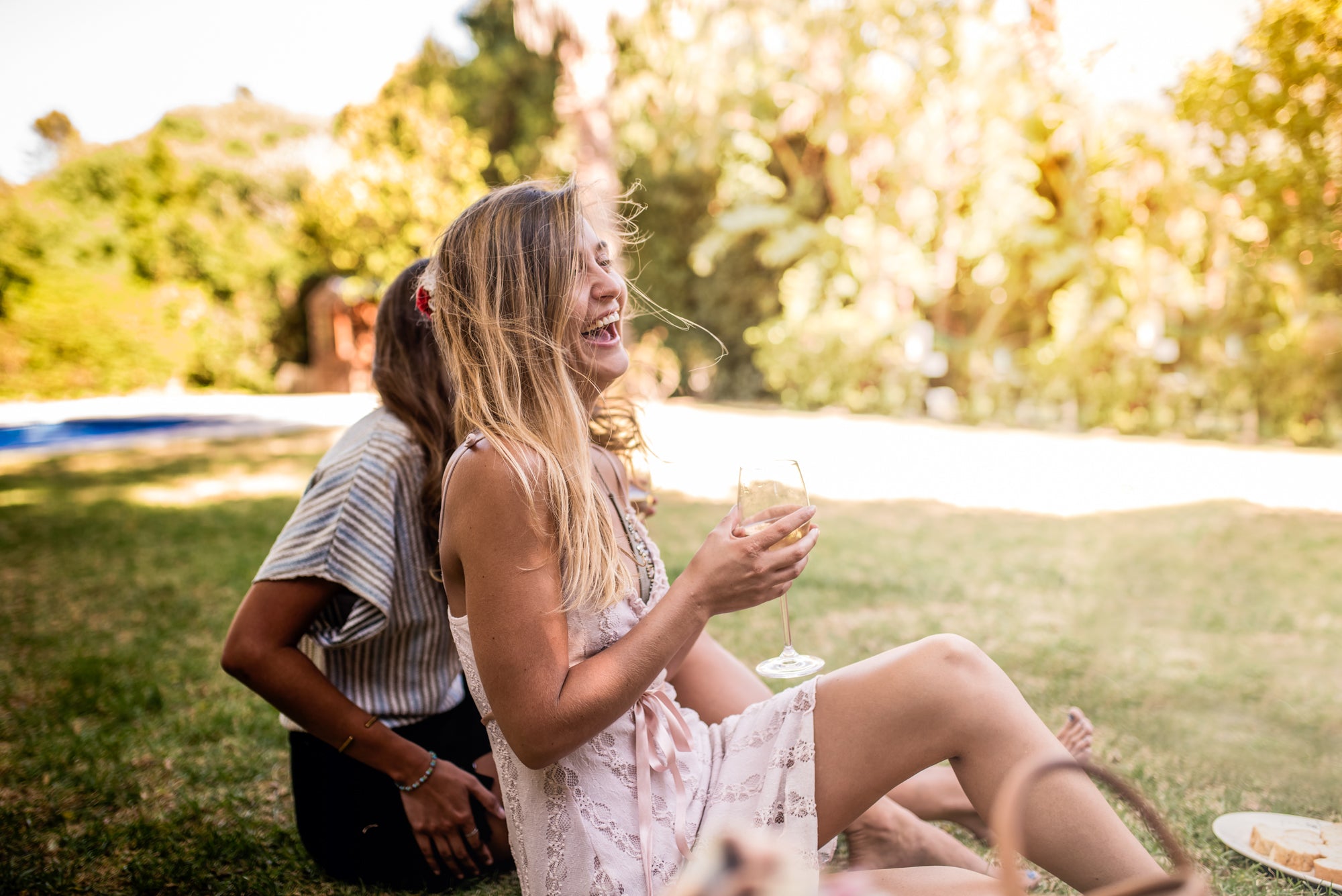 two women laughing and having a picnic in the grass