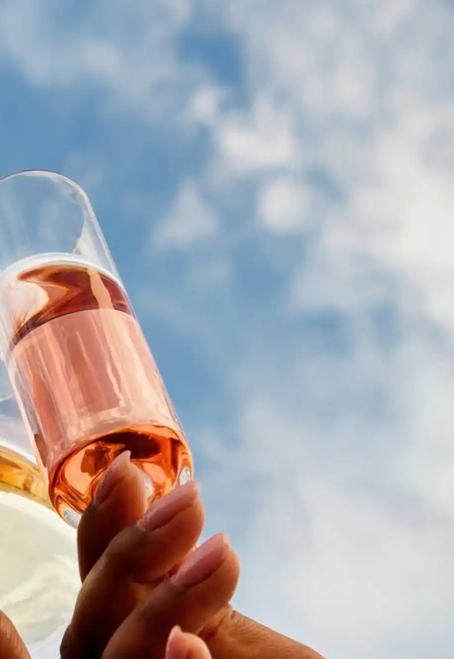 Three glasses of wine coming together for a toast with the sky in the background